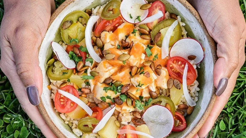 Al Pastor chicken bowl with pineapple, tomatoes, jalapeño and pumpkin seeds over rice