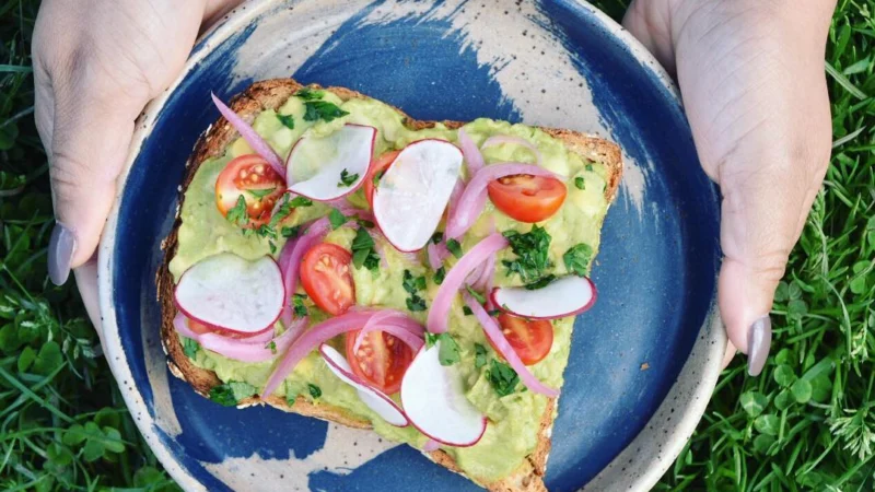 Tostada de aguacate con rábano y tomate en un plato azul