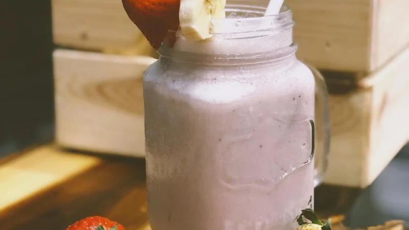smoothie de morango com banana em um pote com morangos frescos