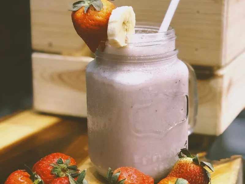 smoothie de fresa y plátano en un tarro con fresas frescas