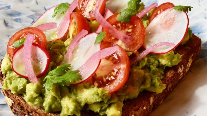Avocado toast on seeded bread with radish, tomato and pickled onion
