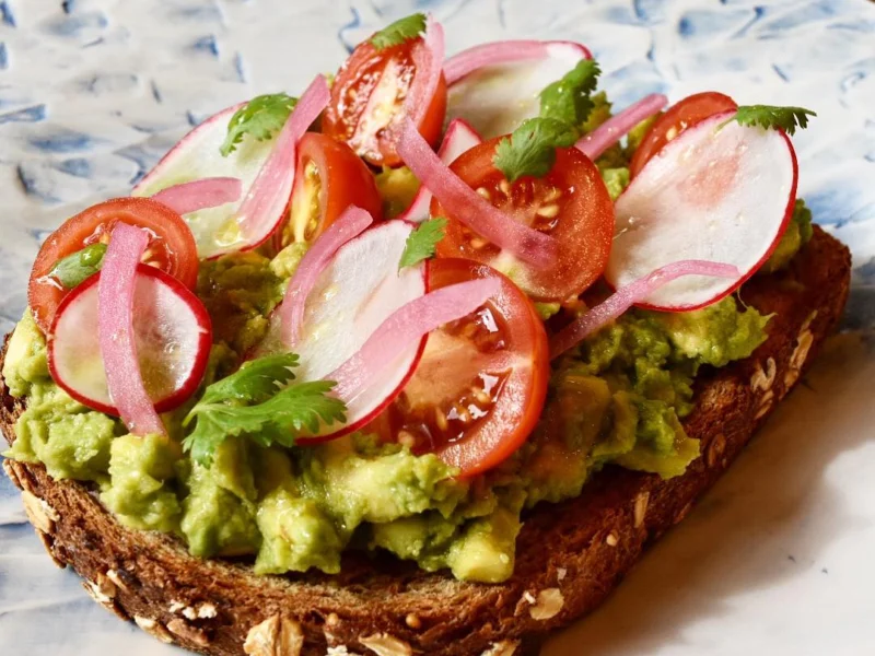Tostada de aguacate en pan de semillas con rábano, tomate y cebolla encurtida